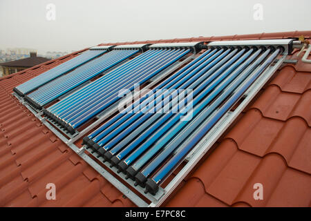 Vakuum-Kollektoren - heisses Wasser mit Sonnenenergie auf rotem Dach des Hauses. Stockfoto