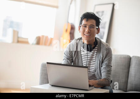 Porträt des Mannes mit Kopfhörern vor laptop Stockfoto