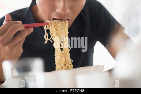 Mann isst Nudeln mit Stäbchen Stockfoto