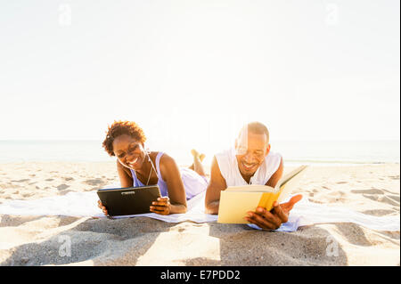 Mann und Frau am Strand lesen Stockfoto