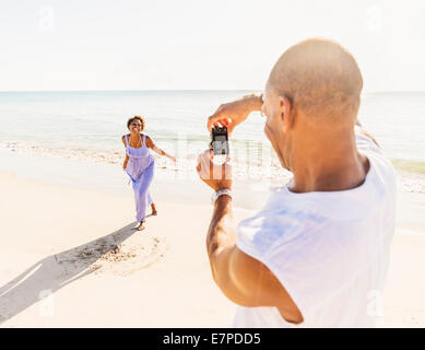 Mann fotografiert Frau am Strand Stockfoto