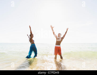 Älteres paar stehen im Meer mit erhobenen Armen Stockfoto