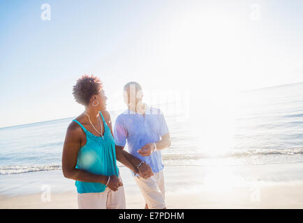 Älteres Paar zu Fuß am Strand Stockfoto