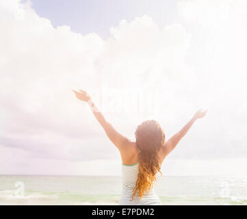 Frau mit erhobenen Armen stand am Strand Stockfoto