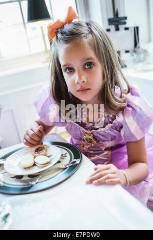 Mädchen (4-5) Essen Cookies am Esstisch Stockfoto