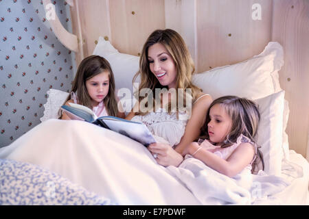 Mutter Lesung Gutenachtgeschichte, ihre Zwillingstöchter (4-5) Stockfoto