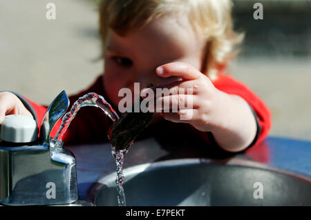 Ein kleiner Junge (2 1/2 Jahre alt) spielen mit einem Wasserbrunnen Stockfoto