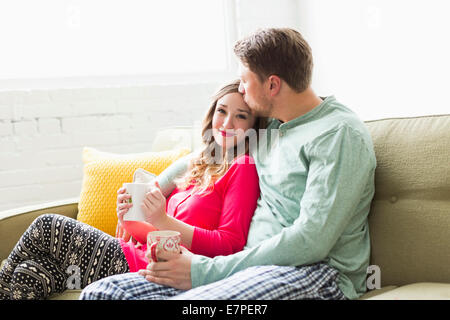 Junges Paar tragenden Pyjamas auf sofa Stockfoto