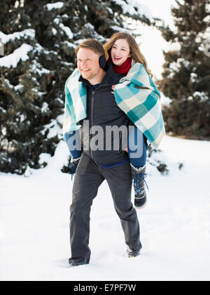 Mann Frau, Salt Lake City, Utah, USA Huckepack-Fahrt im Winterwald Stockfoto