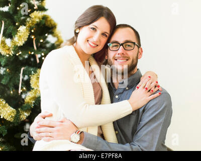 Studioportrait paar vor Weihnachten Baum umarmen Stockfoto