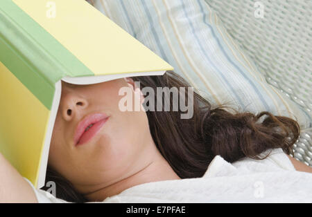 Frau schläft mit Buch auf Gesicht Stockfoto