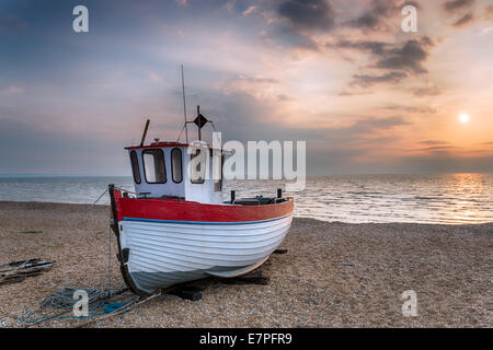 Einem roten und weißen hölzernen Fischerboot am Strand kurz nach Sonnenaufgang Stockfoto