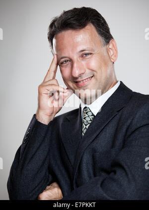 Porträt eines leitenden Geschäftsmann lächelnd auf den grauen Hintergrund Stockfoto