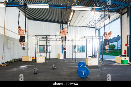 Athleten, die an Gymnastik Ringe hängen Stockfoto