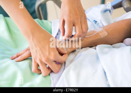 Weiblich-Krankenschwester Tropf auf männliche Patienten Hand anbringen Stockfoto