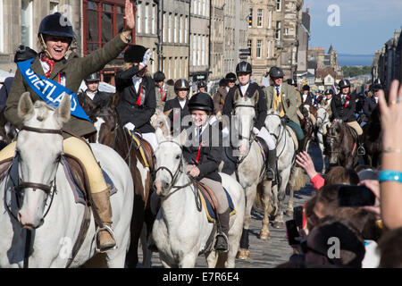 Eine Frau auf einem Pferd winken für Menschen in der Menge auf der Royal Mile, Edinburgh vor dem jährlichen Reiten der feierlichen Märschen. Stockfoto