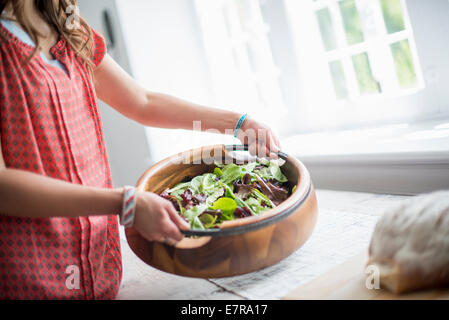 Eine Frau mit Nahrungsmitteln zu einer Tabelle für ein Familienessen vorbereiten. Stockfoto