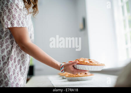 Eine Frau mit Nahrungsmitteln zu einer Tabelle für ein Familienessen vorbereiten. Stockfoto