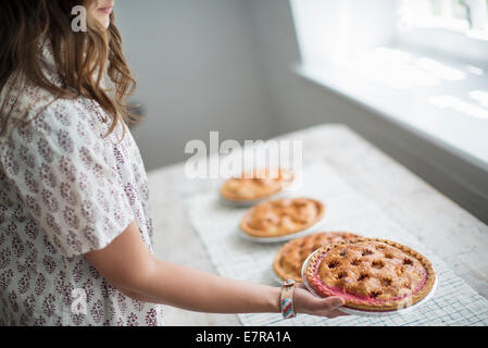 Eine Frau mit Nahrungsmitteln zu einer Tabelle für ein Familienessen vorbereiten. Stockfoto