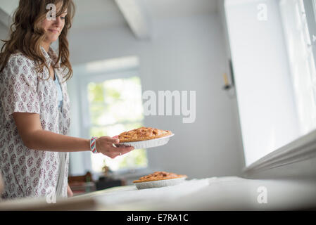 Eine Frau mit Nahrungsmitteln zu einer Tabelle für ein Familienessen vorbereiten. Stockfoto