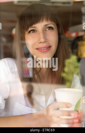 Lächelnde junge Frau im Café mit Kaffee oder Tee Stockfoto