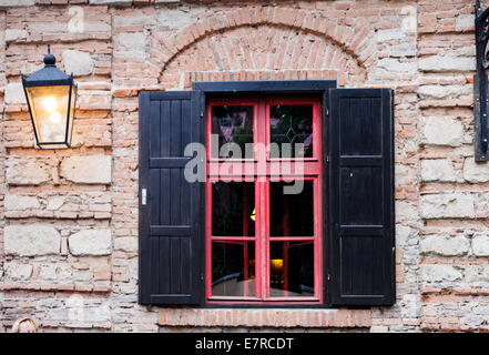 Retro-Fenster mit schwarzen Jalousie im Freien und Brich Stadtmauer Stockfoto