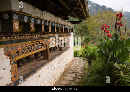 Ost Bhutan, Trashi Yangtse, alte Dongdi Dzong, roten Gladiolen-Blüten und Linie von Gebetsmühlen Stockfoto