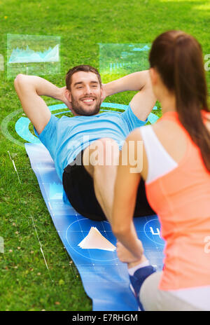lächelnde paar Übungen auf Matte im freien Stockfoto