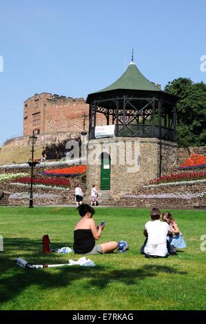 Blick auf den Schlossgarten und Musikpavillon mit der normannischen Burg auf der Rückseite mit Menschen sitzen auf dem Rasen, Tamworth, UK. Stockfoto