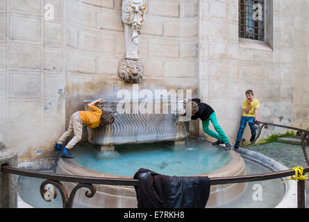 Jungen trinken am Brunnen Stockfoto