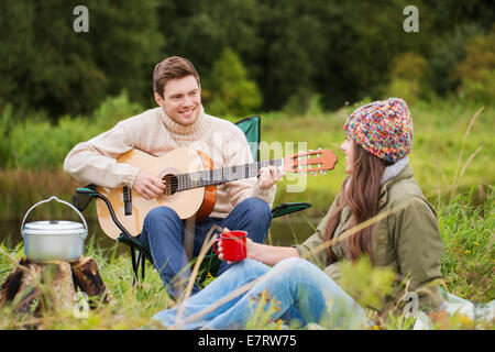 lächelnde paar mit Gitarre auf dem Campingplatz Stockfoto