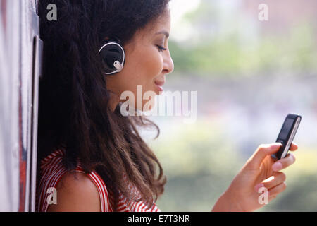 Fröhliche junge Frau im Kopfhörer Musik hören Stockfoto
