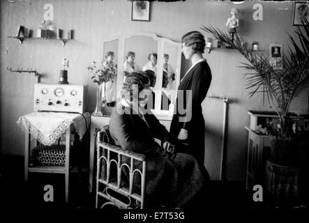 Dieses Bild aus dem Reykjavik der 1930er Jahre zeigt eine Inneneinrichtung mit Frauen in traditioneller isländischer Kleidung, einer Haarspange und einer mit Spitze verzierten Umgebung, die das Design der Häuser während des frühen 20. Jahrhunderts unterstreicht. Stockfoto