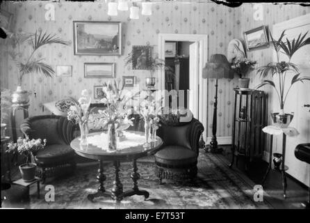 Foto eines Wohnzimmers (Setustofa) in einem Haus in Reykjavik, aufgenommen zwischen 1910 und 1930. Das Bild zeigt die Innenarchitektur und Einrichtung, die typisch für isländische Häuser des frühen 20. Jahrhunderts ist und das kulturelle und häusliche Leben der Zeit widerspiegelt. Stockfoto