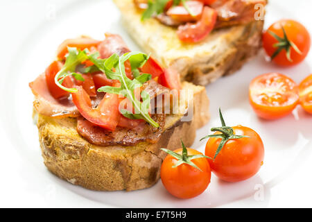 Bruschetta mit gegrilltem Brot, Schinken, Rucola und Kirschtomaten Stockfoto