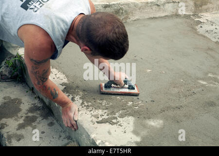 Arbeiter glättet eine Skim-Beschichtung von Zement auf alte Treppe. Stockfoto