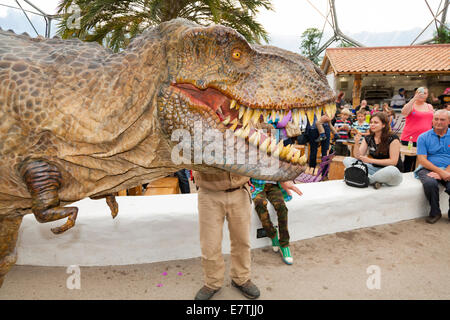 Ein Dinosaurier auf dem losen (mit Wachen) unterhält Kinder & Familien im Eden Project in Bodelva, Saint Austell Cornwall UK Stockfoto
