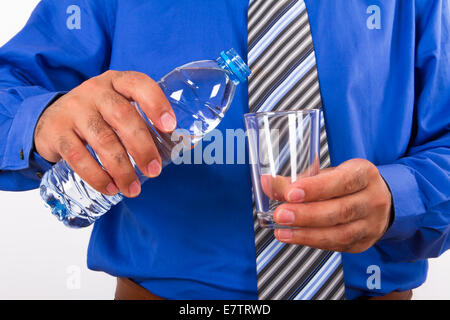 Wasser in Glas aus Kunststoff-Flasche von dem Geschäftsmann. Stockfoto