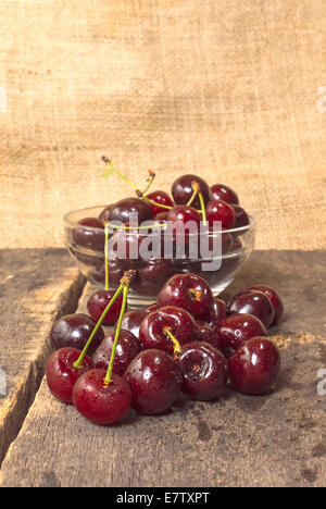 Kirschen auf Holztisch mit Wassertropfen. Stockfoto