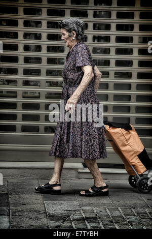 Frau zu Fuß mit ihrem Einkaufswagen in Main Street Gibraltar Stockfoto