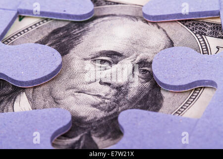 Hundert-Dollar-Banknote zwischen Puzzleteile. Stockfoto