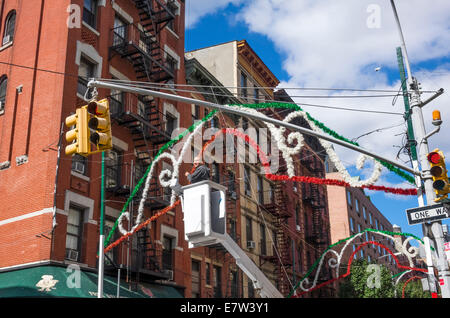 Ein Mann in eine Hubarbeitsbühne Aufstellen von Dekorationen in der Mulberry Street für das fest von San Gennaro in Little Italy in New York City Stockfoto