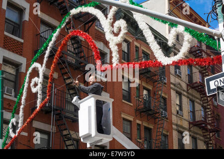 Ein Mann in eine Hubarbeitsbühne Aufstellen von Dekorationen in der Mulberry Street für das fest von San Gennaro in Little Italy in New York Stockfoto