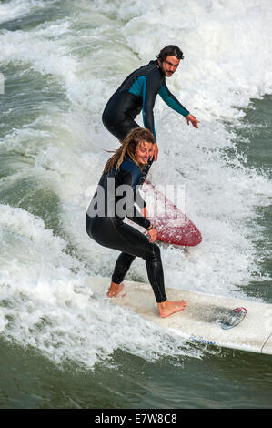 Zwei Surfer in Neoprenanzüge Welle auf Surfbrett zu reiten, da es entlang der Nordseeküste bricht Stockfoto