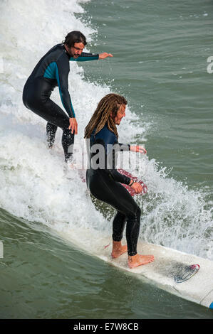 Zwei Surfer in Neoprenanzüge Welle auf Surfbrett zu reiten, da es entlang der Nordseeküste bricht Stockfoto