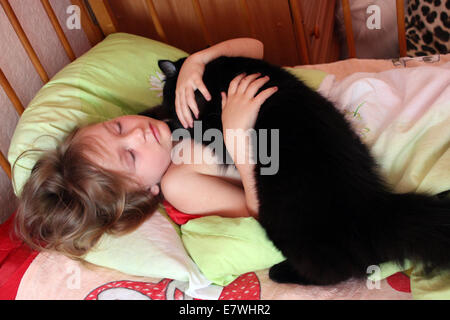 kleines Mädchen spielt mit ihrer Katze in ihrem Bett Stockfoto