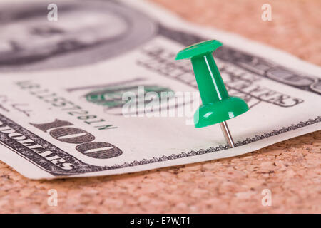 Grüne Stecknadel mit hundert-Dollar-Schein auf Kork-Pinnwand. Stockfoto