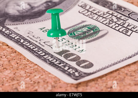 Grüne Stecknadel mit hundert-Dollar-Schein auf Kork-Pinnwand. Stockfoto