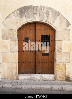 Alte Holztür mit Bogen in gelben Steinmauer Stockfoto