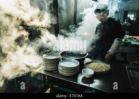 Chinesisch kochen die Nudeln inmitten einer Wolke aus Licht und Dampf. Restaurant. Turpan, Xinjiang, China Stockfoto